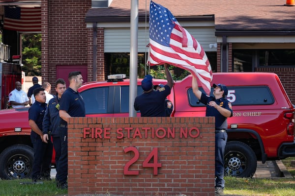 DeKalb County firefighters lower the U.S. flag to half-staff at Fire Station No. 24 to honor Master Firefighter Preston Fant, who died Monday while battling a blaze at an indie film studio. (Ben Hendren for the AJC)