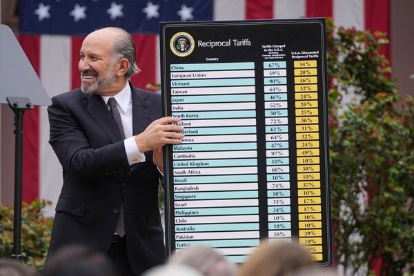Commerce Secretary Howard Lutnick holds a chart as President Donald Trump speaks during an event to announce new tariffs in the Rose Garden at the White House, Wednesday, April 2, 2025, in Washington. (AP Photo/Mark Schiefelbein)