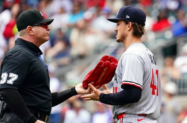 Minnesota Twins pitcher Joe Ryan (41) has his glove checked by umpire Carlos Torres (37) during the third inning of a baseball game against the Minnesota Twins, Saturday, April 20, 2025, in Atlanta. (AP Photo/John David Mercer)