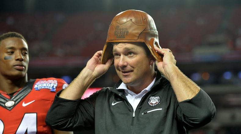 Kirby Smart tries on the Chick-fil-A Kickoff game’s Old Leather Helmet after his first team beat North Carolina at the Georgia Dome in 2016. (AJC file)