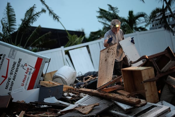FILE - Robert Turick, 68, works to clear household debris that Hurricane Milton storm surge swept from other properties into his canal-facing back yard, in Englewood, Fla., Friday, Oct. 11, 2024. (AP Photo/Rebecca Blackwell, File)