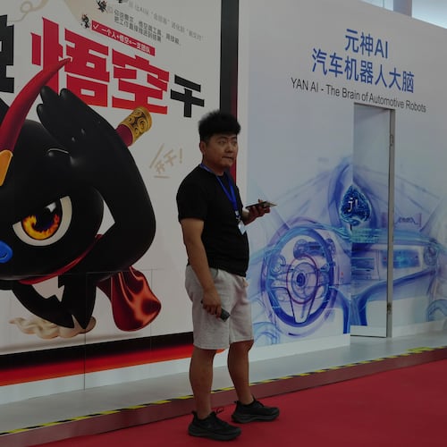 A man stands near a poster promoting the AI agent from Alibaba at the China International Supply Chain Expo in Beijing on Monday, June 22, 2026. (AP Photo/Ng Han Guan)