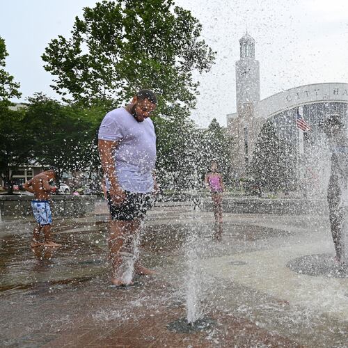 Adam Parker (left), of Suwanee, and his children play in the splash fountain at Town Center Park, Friday, June 30, 2023, in Suwanee. (Hyosub Shin/AJC)