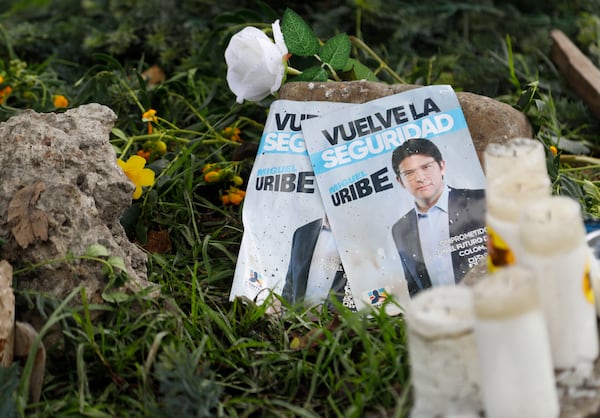Images of Colombian Senator Miguel Uribe Turbay, along with candles and flowers, lay at the site where he was shot during a political rally in Bogota, Colombia, Monday, June 9, 2025. (AP Photo/John Vizcaino)