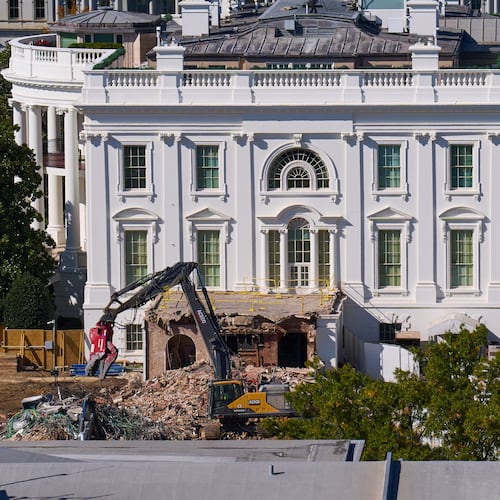 Construction workers, bottom right, atop the U.S. Treasury, watch as work continues on a largely demolished part of the East Wing of the White House, Thursday, Oct. 23, 2025, in Washington, before construction of a new ballroom. (AP Photo/Jacquelyn Martin)
