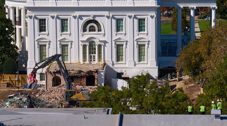 Construction workers, bottom right, atop the U.S. Treasury, watch as work continues on a largely demolished part of the East Wing of the White House, Thursday, Oct. 23, 2025, in Washington, before construction of a new ballroom. (AP Photo/Jacquelyn Martin)