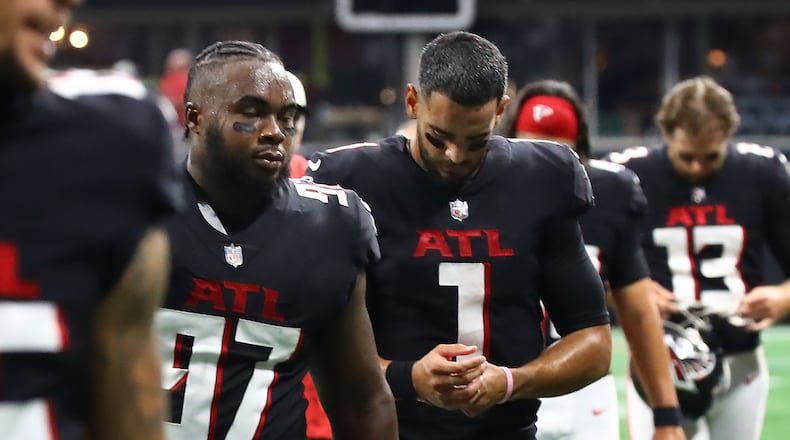 Falcons defensive lineman Grady Jarrett and quarterback Marcus Mariota walk off the field dejected after falling in a 27-26 heartbreaker to the Saints on Sunday in Atlanta. (Curtis Compton / Curtis Compton@ajc.com)