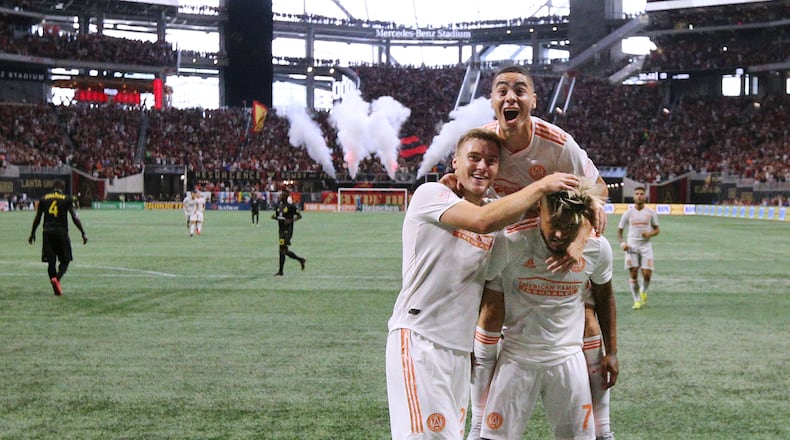 August 19, 2018 Atlanta: Atlanta United forward Josef Martinez (right) celebrates with Franco Escobar and Miguel Almiron on his back after making the MLS season record tieing goal, his 27th, past Columbus Crew defender Jonathan Mensah for a 1-0 lead during the first half in a MLS soccer match on Sunday, August 19, 2018, in Atlanta. The Atlanta United won the game 3-1. Curtis Compton/ccompton@ajc.com