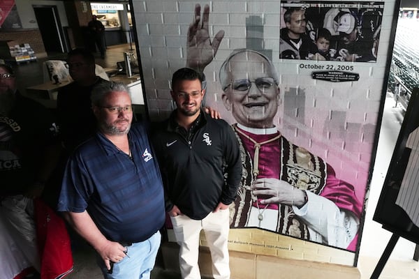 Eddie Schmit III, left, and his son Eddie Schmit IV, right, pose for a photo after a news conference for the Chicago White Sox's commemoration of team fan Pope Leo XIV with a graphic installation at Rate Field before a baseball game between the Seattle Mariners and the White Sox in Chicago, Monday, May 19, 2025. (AP Photo/Nam Y. Huh)