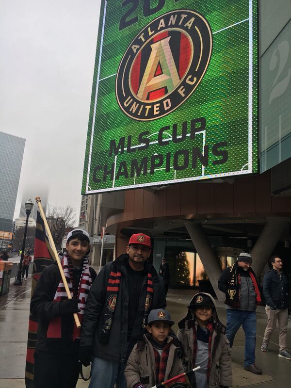 Pedro Rodriguez, 38, pulled his three sons out of school so they could see the parade. The sons, ages 5 to 12, were with him at the big game. (Ben Brasch/AJC Staff)