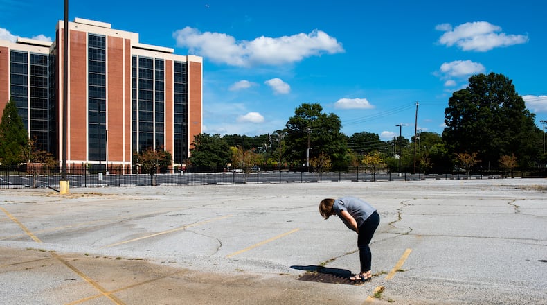 Hannah Palmer, Atlanta southside native, author and coordinator of the non-profit Finding the Flint, looks down the storm drain to see the water running at Virginia Crossings, in downtown East Point.
