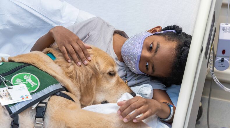Amiaya Brown, 9, snuggles with therapy dog, Flo, in her hospital room at Children's Healthcare of Atlanta Egleston in Decatur. The Canines for Kids program at Children's Healthcare of Atlanta began with one dog, Casper, in 2009 and now has 14 dogs on staff. The dogs visit with the pediatric patients to make their time in the hospital easier.
 SKINNER FOR THE ATLANTA JOURNAL-CONSTITUTION