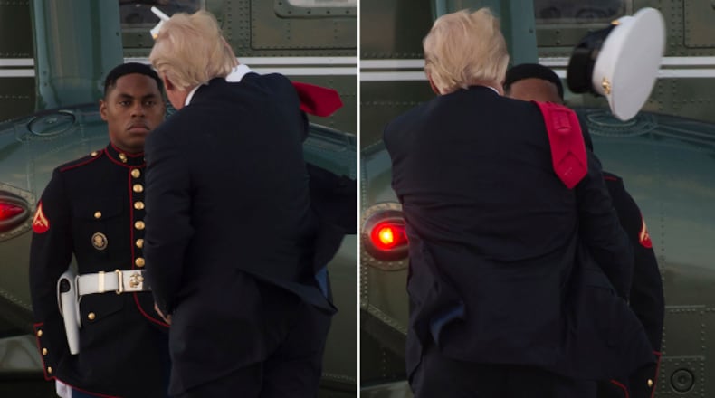 US President Donald Trump tries to catch a hat that the wind had blown from the head of a US Marine guarding Marine One following Trump's arrival at Andrews Air Force Base in Maryland, July 8, 2017, following a 4-day trip to Poland and Germany for the G20 Summit. (SAUL LOEB/AFP/Getty Images)