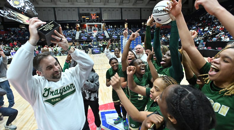 Grayson's head coach Tim Slater holds the championship trophy as the team celebrates their win over North Paulding during GHSA Basketball Class 7A Girl’s State Championship game at the Macon Centreplex, Saturday, Mar. 9, 2024, in Macon. Grayson won 65-44 over North Paulding. (Hyosub Shin / Hyosub.Shin@ajc.com)