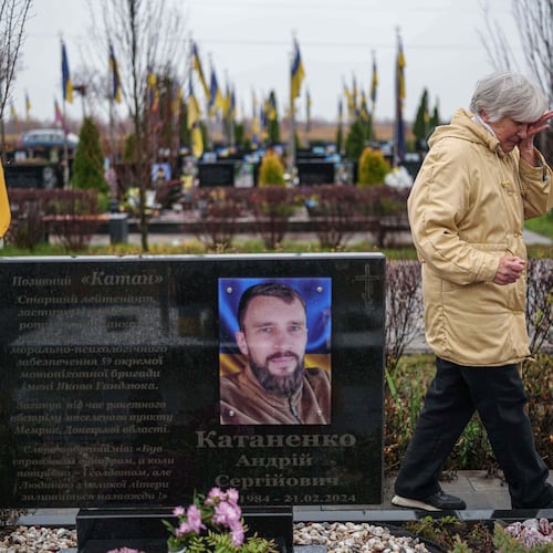 Vira Katanenko, 66, cries while visiting a grave of her son Andrii Katanenko, a Ukrainian serviceman of 59th brigade at the cemetery in Bucha, Ukraine, on Sunday, Nov. 23, 2025. (AP Photo/Evgeniy Maloletka)