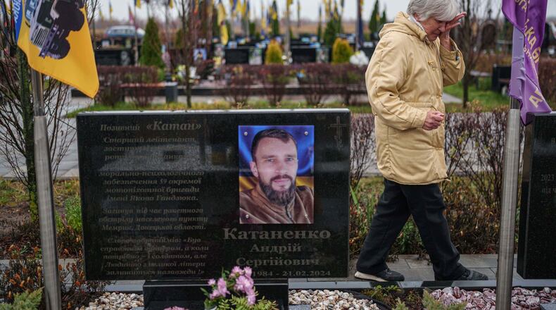 Vira Katanenko, 66, cries while visiting a grave of her son Andrii Katanenko, a Ukrainian serviceman of 59th brigade at the cemetery in Bucha, Ukraine, on Sunday, Nov. 23, 2025. (AP Photo/Evgeniy Maloletka)
