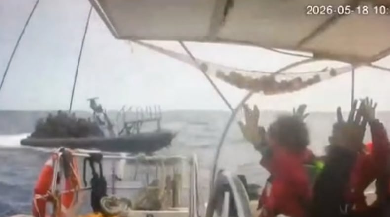 This grab from CCTV footage shows activists aboard a flotilla boat with their hands in the air as a boat approaches one of more than 50 vessels that departed from the port of Marmaris, Turkey, last week in what organizers of the Global Sumud Flotilla described as the final leg of their planned journey to Gaza's shores, in international waters Monday, May 18, 2026. (Global Sumud Flotilla via AP)