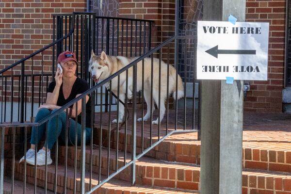 Amy Cate waits for her husband outside  St. Martin in the Fields Episcopal Church with her dog Diesel before casting her vote on Tuesday, Nov. 7, 2023.  (Steve Schaefer/steve.schaefer@ajc.com)
