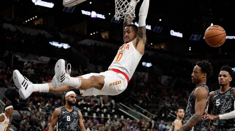 Atlanta Hawks forward John Collins (20) scores over San Antonio Spurs guard DeMar DeRozan, second from right, during the first half of an NBA basketball game in San Antonio, Friday, Jan. 17, 2020. (AP Photo/Eric Gay)
