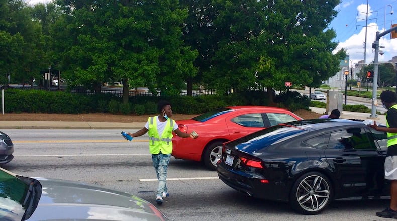 Quanarius Hosch, 15, has just made a sale at the corner of Northside Drive and Joseph E. Boone Blvd and is hoping to make another before the light changes. Photo BILL TORPY