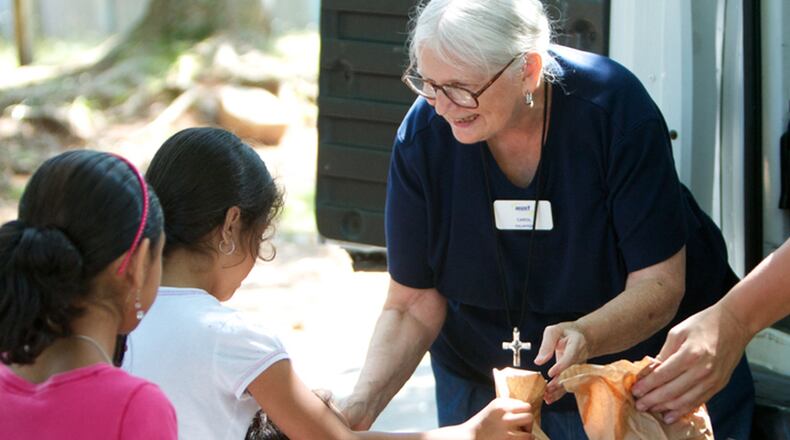 MUST summer lunch program founder Carol Hunt hands out sack lunches to children.