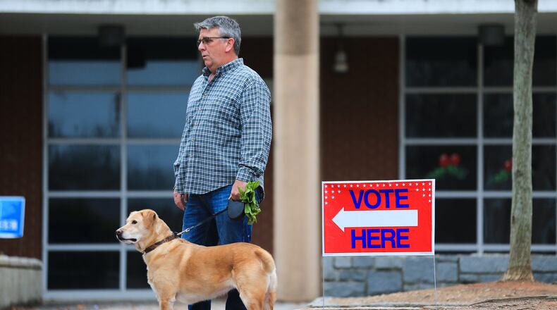Harold Duvall gets pleasant weather Tuesday morning as he waits with his dog Riley for his wife to vote at Grady High School. But wet weather is on the way.