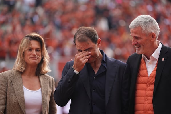 Rafa Nadal, center, stands between French tennis federation President Gilles Moretton, right, and is Roland-Garros tournament director Amelie Mauresmo, during a farewell ceremony at center court Philippe-Chatrier, at the Roland-Garros stadium, in Paris, Sunday May 25, 2025. (AP Photo/Lindsey Wasson)