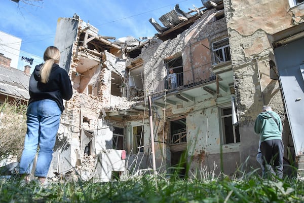 People look at a damaged residential building following Russian air attack in Lviv, Ukraine, Saturday, July 12, 2025. (AP Photo/Mykola Tys)