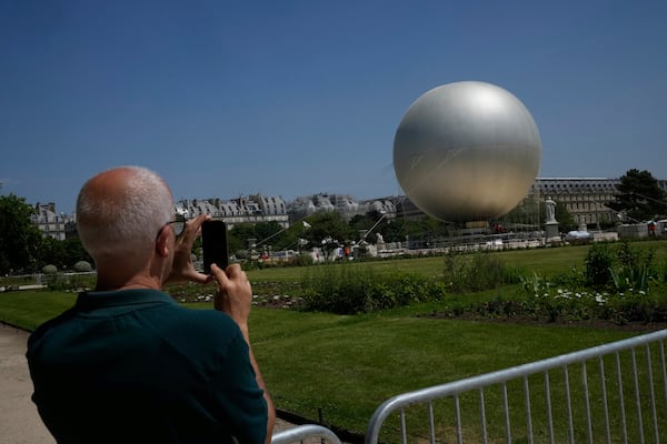 A man takes a snapshot of the Olympic cauldron at the Tuileries Gardens, ahead of its nightly summer relaunch starting June 21, in Paris, Thursday, June 12, 2025. (AP Photo/Michel Euler)