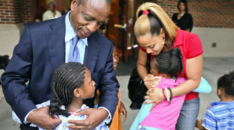 DeKalb County Schools Superintendent, Michael Thurmond (left) and Ronald E. McNair Discovery Learning Academy technology teacher, Shanique Worthey (right) hug elementary children as they arrive for classes at McNair high school.