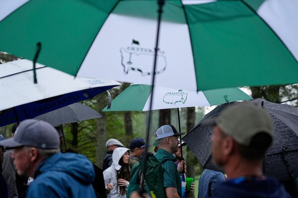 Patrons walks under umbrellas along the 13th green during a practice round at the Masters golf tournament, Monday, April 7, 2025, in Augusta, Ga. (AP Photo/Ashley Landis)