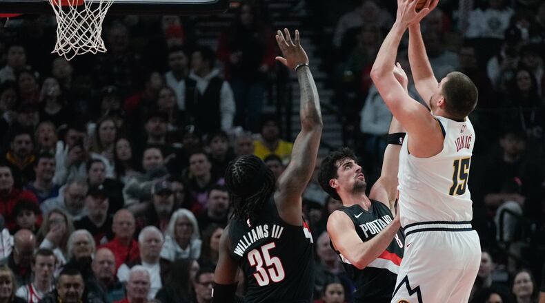 Portland Trail Blazers forward Deni Avdija (8) tries to block a shot by Denver Nuggets center Nikola Jokić (15) during the first half of an NBA basketball game Friday, Feb. 20, 2026, in Portland, Ore. (AP Photo/Jenny Kane)