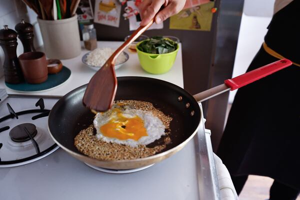 Crack the egg into the wok or skillet and cook until curds just begin to form, then add the rice. Stir, gently smashing the rice so that any clumps are broken up, and cook until the egg is almost cooked through, about 2 minutes. (Natrice Miller/AJC)