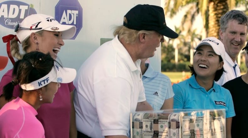 This Nov. 18, 2006 file photo shows Donald Trump, center, putting his hands on a box of money while posing for a photo with the eight golfers who qualified for the final round following the third round of the LPGA ADT Championship at the Trump International Golf Club in West Palm Beach, Fla. Also present, from left to right, are: Mi Hyun Kim, of South Korea, Natalie Gulbis and il Mi Chung, also of South Korea. The U.S. Women's Open will be played next week at a golf course in New Jersey owned by President Trump. The USGA awarded the site in 2012 and later came under pressure from women's groups and three Democratic U.S. senators to move the event because of Trump's comments about women and minorities. It's uncertain if the president will attend the tournament in Bedminster, New Jersey. (AP Photo/Lynne Sladky)