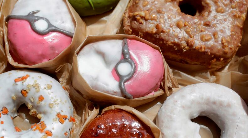 In this Friday, July 22, 2016, photo, Pecha Berry Pokeseed doughnuts, top left and center, are displayed in a box of doughnuts from Doughnut Plant, in New York. From doughnut shops to zoos, businesses and organizations are finding creative ways to capitalize on “Pokemon Go.” (AP Photo/Mark Lennihan)