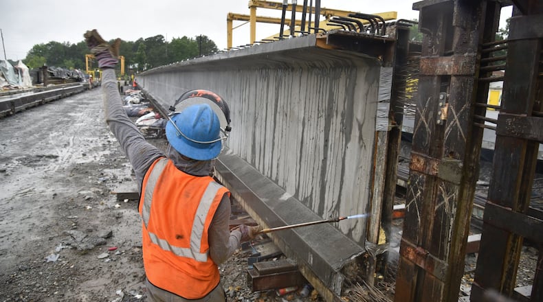 Workers simultaneously cut strands of steel rebar that connect giant girders at Standard Concrete Products’ Atlanta plant. The family-owned company produced and delivered 61 bridge girders to the I-85 project over a 15 day stretch. HYOSUB SHIN / HSHIN@AJC.COM