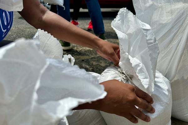 A volunteer ties a sandbag for New Orleans residents, Wednesday, July 16, 2025, anticipating heavy rain from a tropical weather system moving toward the Gulf Coast. (AP Photo/Stephen Smith)