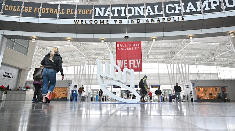 Travelers pass by national championship displays at Indianapolis International Airport on Thursday. Downtown Indianapolis is set to host the 2022 College Football Playoff title game between Georgia and Alabama. (Hyosub Shin / Hyosub.Shin@ajc.com)