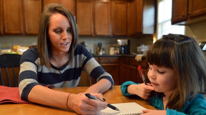 Ashley Cline helps her daughter, Avery,4, with a handwriting exercise at their home in Canton. Cline is the wife of a public school teacher who is speaking out against Georgia’s new health care plan for state employees. Avery attends occupational therapy for help developing her fine motor skills. Under the new plan the cost went from $25.00 to $130.00. BRANT SANDERLIN /BSANDERLIN@AJC.COM