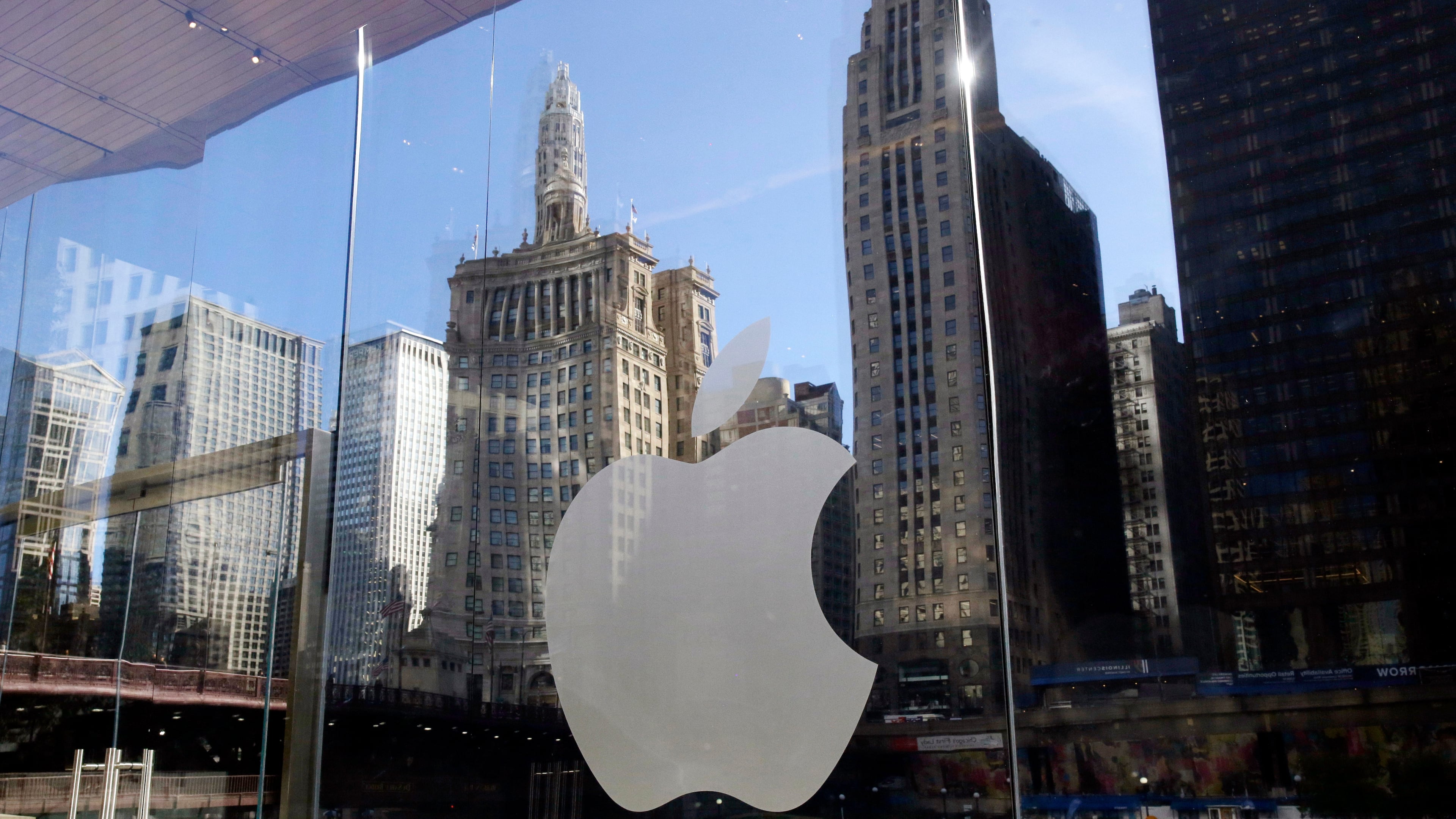 FILE - Buildings are reflected behind the logo at an Apple Store, in downtown Chicago, Oct. 19, 2017. (AP Photo/Kiichiro Sato, File)