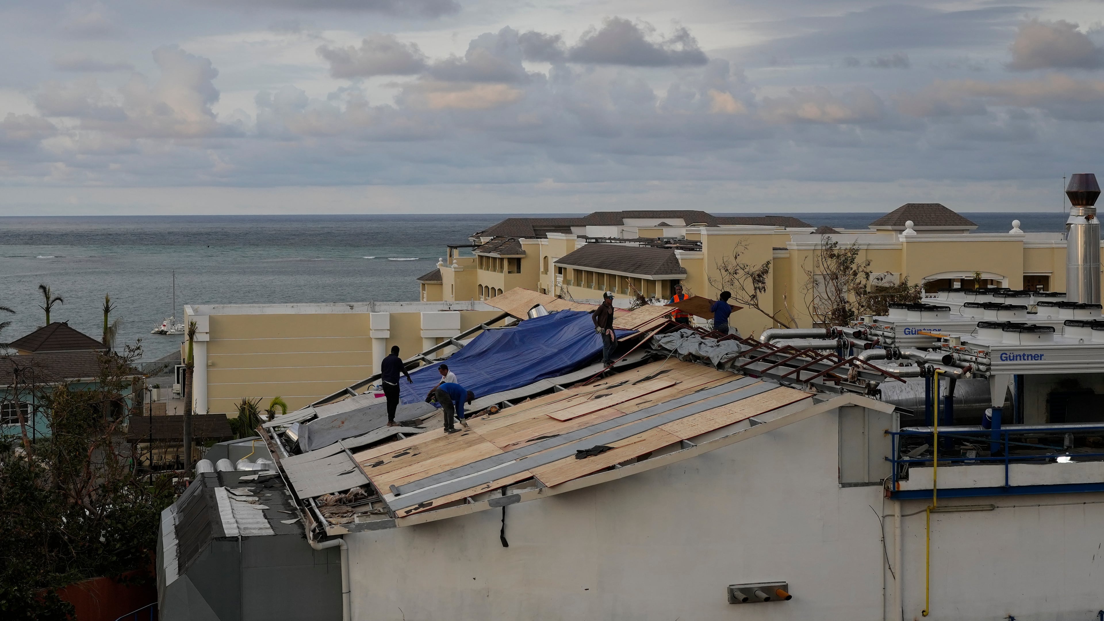 People repair the roof of a resort in Montego Bay, Jamaica, Friday, Oct. 31, 2025, in the aftermath of Hurricane Melissa. (AP Photo/Matias Delacroix)