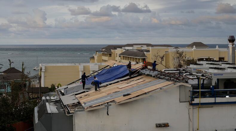 People repair the roof of a resort in Montego Bay, Jamaica, Friday, Oct. 31, 2025, in the aftermath of Hurricane Melissa. (AP Photo/Matias Delacroix)