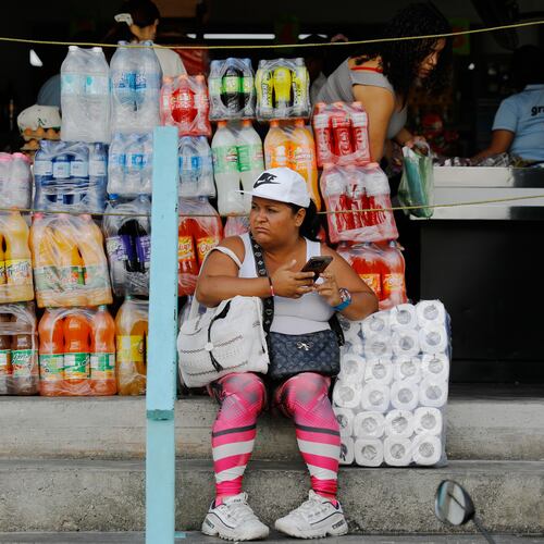 A woman sits in front of a store in the Petare neighborhood of Caracas, Venezuela, Wednesday, Jan. 7, 2026. (AP Photo/Cristian Hernandez)