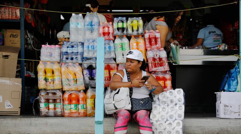A woman sits in front of a store in the Petare neighborhood of Caracas, Venezuela, Wednesday, Jan. 7, 2026. (AP Photo/Cristian Hernandez)
