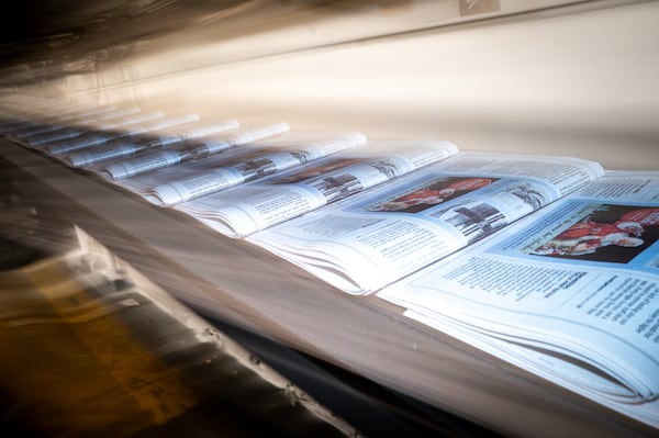 A steady stream of copies of the final Sunday run of The Atlanta Journal-Constitution is shuttled away from the printing press. (Arvin Temkar/AJC)