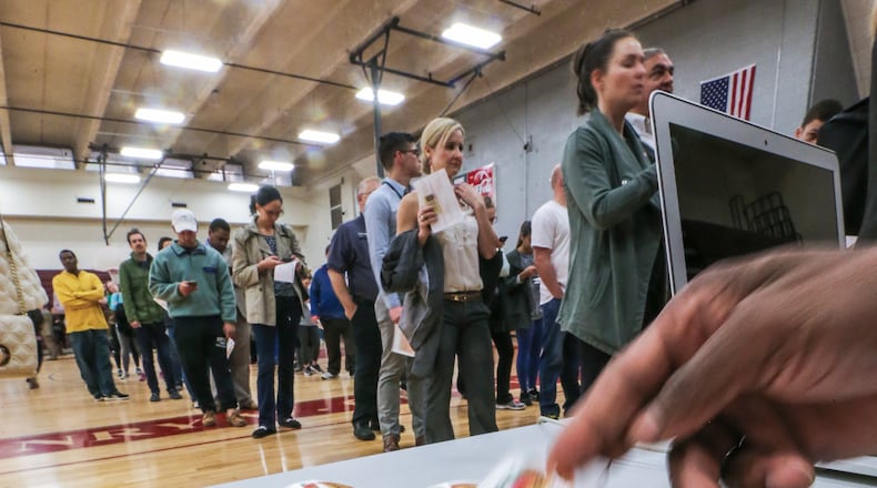 Poll worker DeCarlos Bennett hands out stickers to voters at Grady High School in Atlanta in 2016. JOHN SPINK /JSPINK@AJC.COM