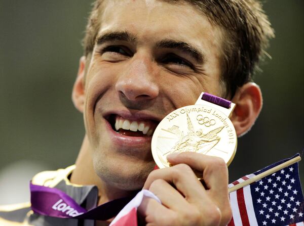 FILE - United States' Michael Phelps poses with his gold medal for the men's 4x200-meter freestyle relay swimming final at the Aquatics Centre in the Olympic Park during the 2012 Summer Olympics in London, Tuesday, July 31, 2012. (AP Photo/Matt Slocum, File)