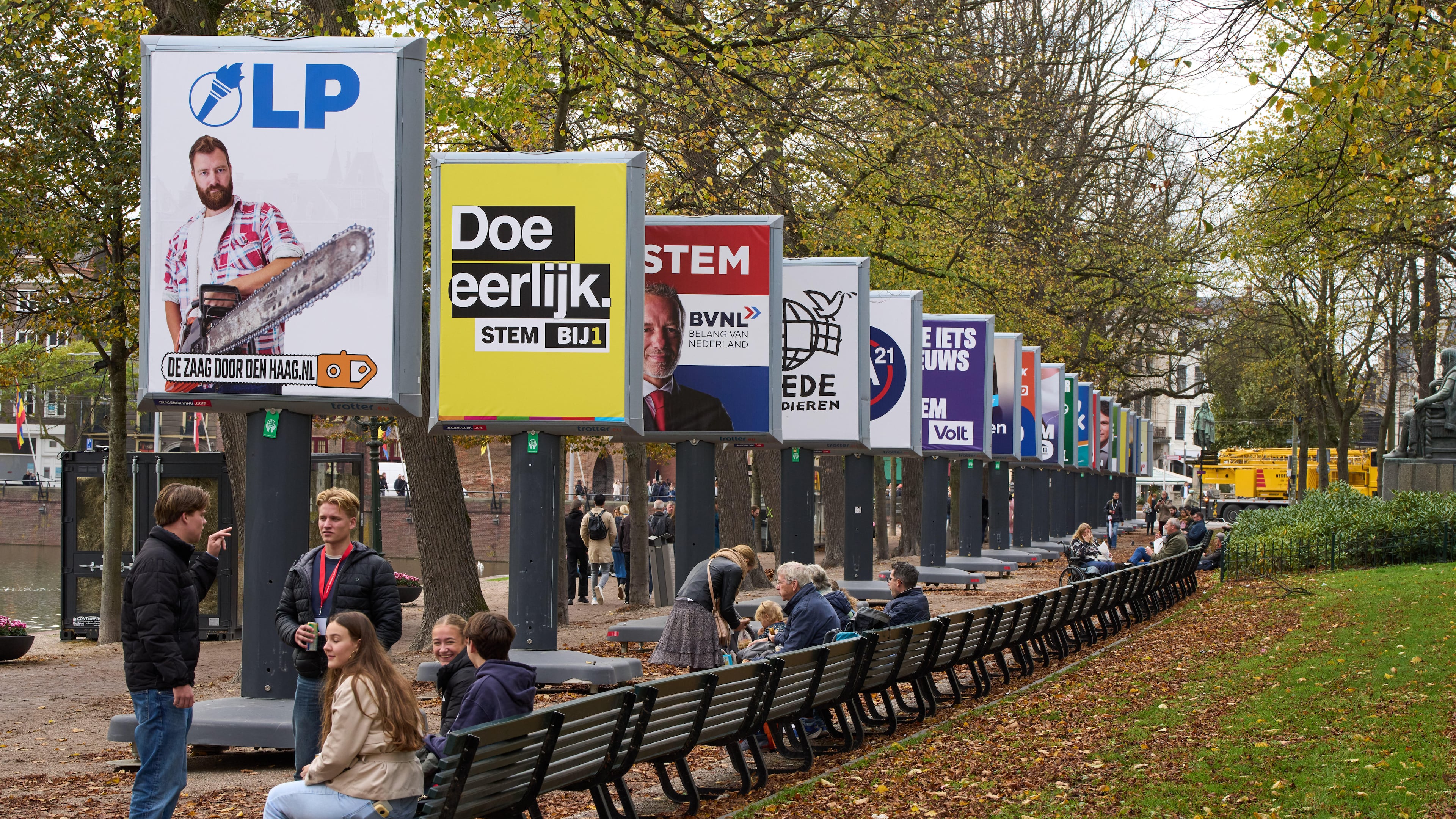 People enjoy the autumn weather next to some of the election billboards of 26 of the 27 political parties participating in the Oct. 29 general elections in The Hague, Netherlands, Wednesday, Oct. 22, 2025. (AP Photo/Peter Dejong)