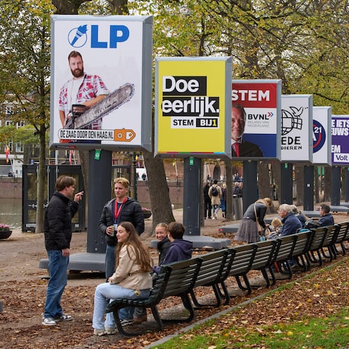 People enjoy the autumn weather next to some of the election billboards of 26 of the 27 political parties participating in the Oct. 29 general elections in The Hague, Netherlands, Wednesday, Oct. 22, 2025. (AP Photo/Peter Dejong)