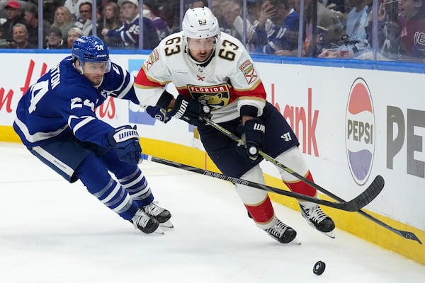 Florida Panthers forward Brad Marchand (63) and Toronto Maple Leafs forward Scott Laughton (24) vie for control of the puck during the third period of Game 1 in an NHL hockey second-round playoff series in Toronto, Monday, May 5, 2025. (Nathan Denette/The Canadian Press via AP